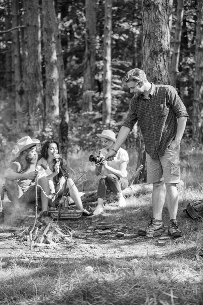 Turister dela tankar om vandringen sitta på loggen. Picknick med vänner i skogen nära brasa. Företaget har vandring picknick natur bakgrund. Vandrare dela intryck av promenad skog. Sommaren tradition — Stockfoto