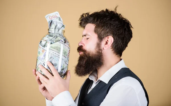 Milovník peněz. Brutální obchodník líbá sklenici s penězi. Vousatý muž šetřící peníze v prasátko. Je nenasytný za peníze — Stock fotografie