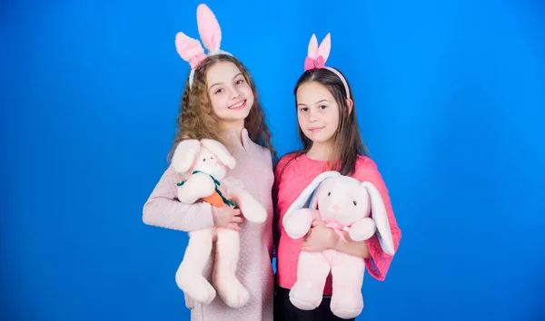 Esperanza amor y vida alegre. Niños con juguetes de conejito sobre fondo azul. Hermanas sonriendo lindo traje de conejito. Difundir alegría y felicidad alrededor. Amigos niñas con orejas de conejo celebran la Pascua — Foto de Stock