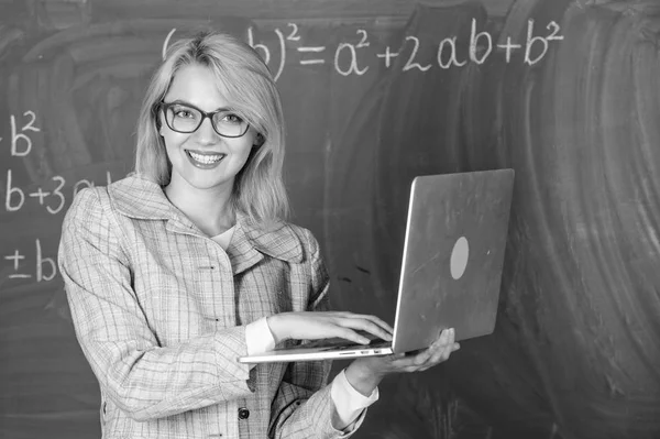 Вчителька в окулярах тримає ноутбук, що серфінгує Інтернет. Освітянка розумна розумна леді з сучасним ноутбуком, що шукає інформацію крейдяного фону. Навчитися легко. Концепція цифрових технологій — стокове фото