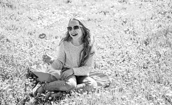 밝은 얼굴에 여자 야외 레저 지출. 패션 개념입니다. 어린이 선글라스 골 판지 초원에서 포토 세션에 대 한 입술을 미소와 함께 포즈. 소녀는 grassplot, 녹색 배경에서 잔디에 앉아 — 스톡 사진