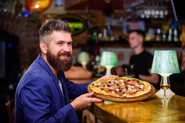 Hipster client sit at bar counter. Man received delicious pizza. Enjoy your meal. Cheat meal concept. Hipster hungry eat italian pizza. Pizza favorite restaurant food. Fresh hot pizza for dinner