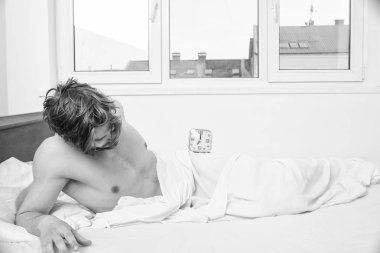 Sopa uyku aynı zamanlama zaman uyan yatma vakti. Adam uykulu tıraşsız sakallı yüzü dinlenme battaniye ile örtülü. Adam yorgun ihtiyaç daha fazla zaman yenilemek için çok bitkin. Adam tıraşsız yatak çalar saat ile yatıyordu.