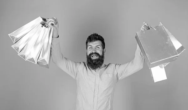 Hombre con barba elegante y bigote llevando bolsas de compras. Ganador del certificado de regalo boutique de lujo aislado sobre fondo azul. Hombre barbudo en camisa rosa con cara alegre, concepto de felicidad — Foto de Stock