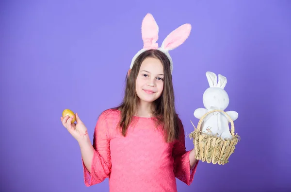 Ostereiersuche im Rahmen des Festes. Mädchen kleines Kind Osterhasen Accessoire halten gefärbte Eier. Herkunft des Osterhasen. Ostersymbole und Traditionen. spielerisches Kind mit Stofftier. Frühjahrsferien — Stockfoto