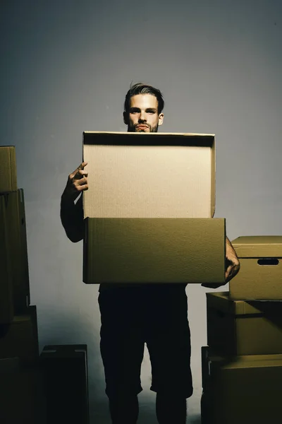 Guy holds boxes near chest, copy space. Man with beard