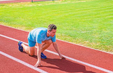 Nasıl yayınlanmaya başlaması. Profesyonel atlet spor ipuçları. Adam atlet runner standı düşük başlangıç pozisyonu stadyum yolu. Zafer için çaba. Runner gitmeye hazır. Yetişkin runner hazırlamak Stadyumu at yarışı