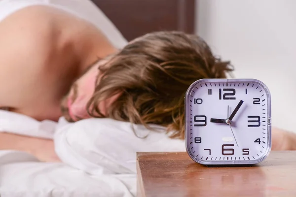 Jovem alegre está acordando depois de dormir de manhã. Homem sentindo dor nas costas na cama depois de dormir. Masculino na casa . — Fotografia de Stock