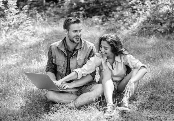 Çift gençlik eğlence dizüstü bilgisayar ile açık havada harcamak. Modern teknolojileri online ve herhangi bir çevre koşulları çalışmalarına olmak için fırsat verir. Adam ve kız dizüstü bilgisayar ekranına bakarak. Doğa en iyi çalışma alanı — Stok fotoğraf