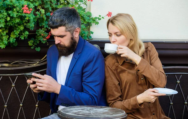 using phone while date. Morning coffee. woman and man with beard relax in cafe. Couple in love on romantic date. Brutal bearded hipster and girl drink coffee. First meet of girl and mature man