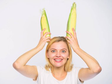 Kız neşeli oynak ruh tavşan kulakları olgun Mısır tutun. Gıda vejetaryen ve sağlıklı organik ürün. Hasat ve eğlenceli. Vejetaryen beslenme kavramı. Kadın beyaz zemin üzerine sarı Mısır Mısır koçanı tutun