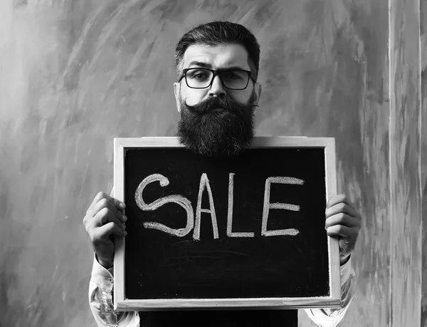 Bearded man, brutal caucasian hipster holding sale inscription on blackboard — Stock Photo, Image