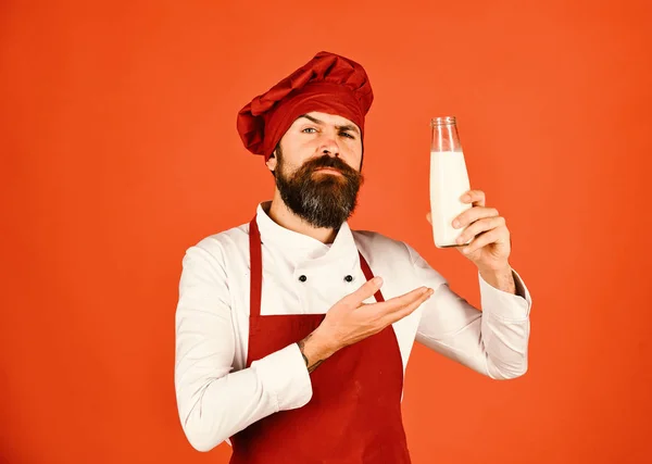 Koka med stolt ansikte i vinröd uniform presenterar mjölk — Stockfoto