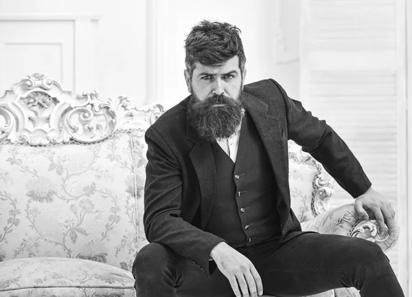 Concepto de estilo de vida Elite. Macho atractivo y elegante en cara seria y expresión reflexiva. Hombre con barba y bigote con traje clásico, se sienta en un sillón o sofá a la antigua —  Fotos de Stock