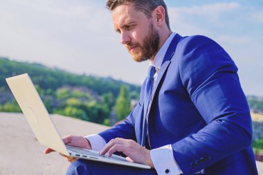 Oranları online satış ipuçları artırın. İşadamı sörf internet veya yanıt e-postalar ile dizüstü bilgisayar açık havada oturup süre. Nasıl yüksek yanıt oranları almak. Internet Pazarlama Yöneticisi mavi gökyüzü arka plan çalışır?