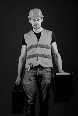 Tamirci, tamirci katı yüz gider ve profesyonel ekipman ile çanta taşır. Profesyonel tamirci kavramı. Araç kutusu ve araç, mavi arka plan ile bavul kask, kask içinde adam tutar