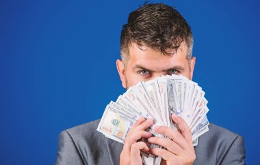 Kolay nakit krediler. İşadamı nakit para var. Zenginlik ve refah kavramı. Nakit para kolay ve hızlı bir şekilde almak. Para gibi kokuyor. Resmi takım elbise tutun doları banknot yığını mavi arka plan