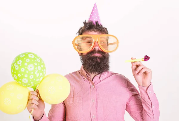 Party concept. Hipster in giant sunglasses celebrating birthday. Guy in party hat with party horn celebrates. Man with beard and mustache on happy face holds air balloons, white background — Stock Photo, Image