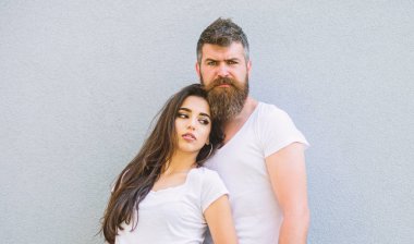 Kaç arkadaş birlikte takılmak. Gençlik şık kıyafet basit ama modern. Genç ve şık. Çift beyaz gömlek gri duvara yakın kucaklamak. Acımasız ve şık moda kız takılmak hipster sakallı