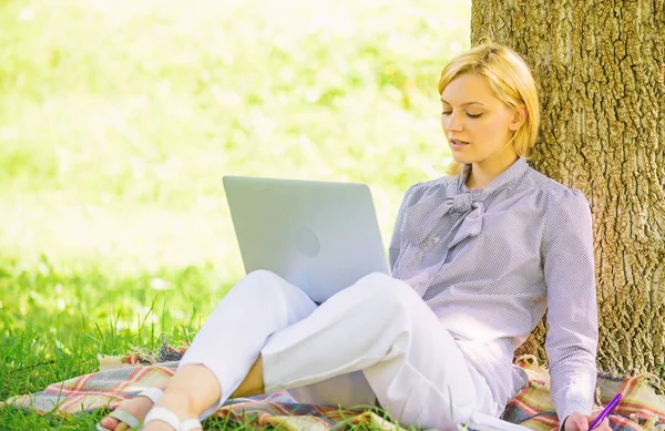 Açık havada faydaları iş. Eğitim teknolojisi ve internet kavramı. Dizüstü bilgisayar işleriyle açık havada ağaç gövdesinde yağsız olan kadın. Park içinde laptop ile kız iş çimenlerin üzerinde oturmak. Doğal ortamda office