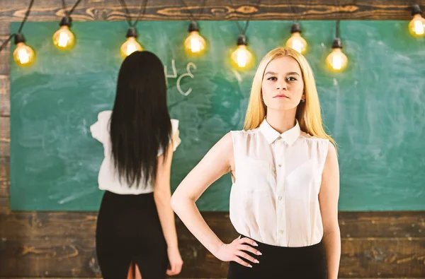 Student, docent in formele slijtage staan in de klas. Meisje kijkt vol vertrouwen terwijl dame schrijven op schoolbord achtergrond, intreepupil. Aantrekkelijke vrouwen voorbereiden van de les. Studenten en stagiairs concept — Stockfoto