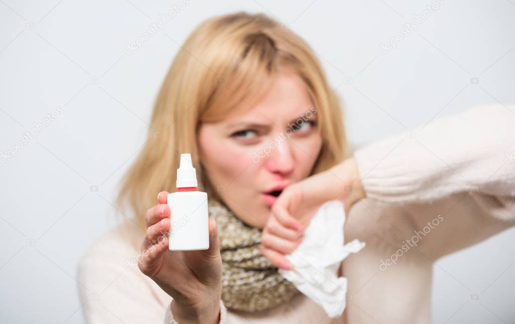 Squeeze twice in each nostril as needed. Ill woman spraying medication in nose. Unhealthy girl using nasal spray for runny nose. Treating cold or allergic rhinitis. Girl nursing nasal cold or allergy