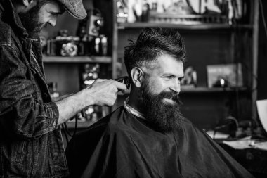 Clipper 'la berber müşterinin ensesinde saç kesiyor. Saç makasıyla berber, sakallı adamın kuaför geçmişi üzerinde çalışıyor. Hipster müşteri saçını kestiriyor. Hippi saç stili konsepti