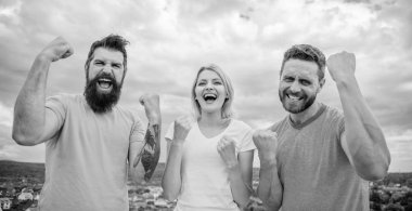 Başarabiliriz. Kadınlar ve erkekler başarılı görünüyor. Zafer gökyüzü geçmişini kutluyorlar. Başarını kutla. Başarılı bir takım kurmanın yolları. Üçlü, yumruklarını kaldırarak mutlu duruyor. Kazanan takımın davranışları