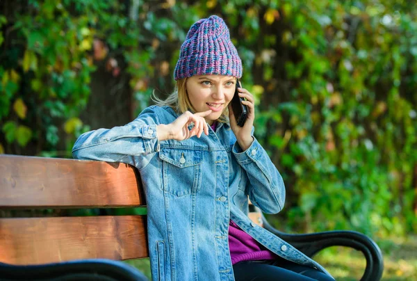 Hipster woman speak on phone. Girl has mobile phone conversation in park. relax on bench in srpring. waiting for boyfriend. Sharing happy news with friend. woman in great mood today. denim fashion