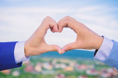 Kalp şekli hareketi simgesinin aşk ve romantizm erkek elinde. Kalp şekli mavi gökyüzü arka planda bir alkış. Aşk sembolü kavramı. El kalp hareketi parmaklarını kullanarak şekil oluşturur