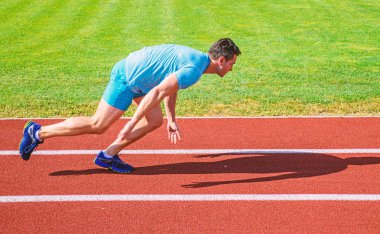 Hareket halinde sadece yarışın başlamasından sonra yakalanan koşucu. Runner sprint yarışı Stadyumu'nda. Nasıl yayınlanmaya başlaması. Alttan yukarıya ittirmek hız kavramı. Adam atlet runner itmek konum stadyum yolu güneşli gün başlamak uzakta