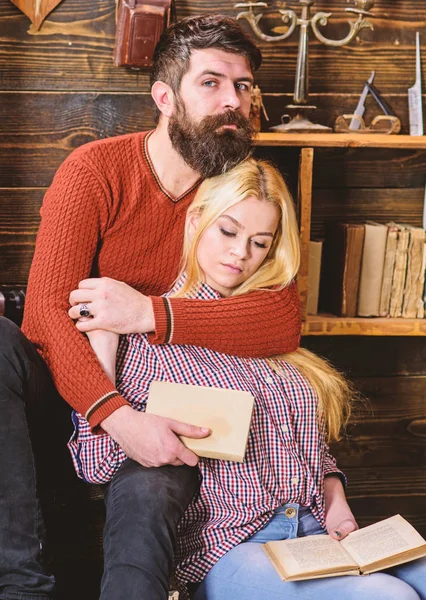 Romantic evening concept. Couple in wooden vintage interior enjoy poetry. Couple in love reading poetry in warm atmosphere. Lady and man with beard on dreamy faces hugs and reading romantic poetry