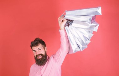 Satış sezon indirimlerle alışveriş adam. Sakal ve bıyık tutan alışveriş torbaları, kırmızı arka planı olan adam. Mutlu yüz hipster bağımlısı alışveriş veya Alışverişkoliğin. Alışveriş kavramı