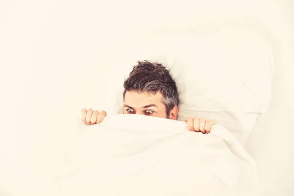 Nightmare concept. Guy hides face under blanket.