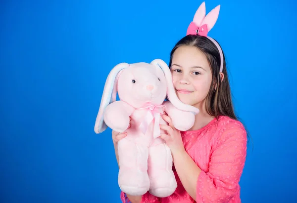 Precioso conejito juguetón niño abraza juguete suave. Accesorio de orejas de conejo. Conejita con lindo juguete sobre fondo azul. Niño sonriendo jugar conejito juguete. Han bendecido Pascua. Adéntrate en el espíritu de Pascua. Feliz infancia. —  Fotos de Stock
