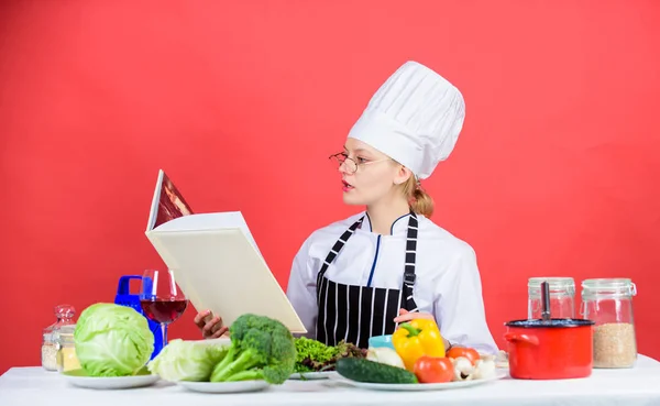 Going to cook something special. Pretty woman reading cook book in kitchen. Lady cook looking for cooking recipe in cookbook. Cute cook housekeeper at kitchen table