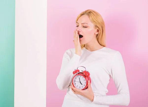 Oversleeping side effects is too much sleep harmful. Girl yawning face just woke up holds alarm clock pink background. Bad sleep habits and effects on your life. Lack of sleep bad for your health