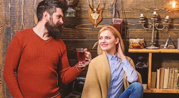 Mujer y hombre en caras sonrientes disfrutar de un ambiente acogedor con bebidas calientes. Concepto de comodidad. Pareja pasar la noche agradable, fondo interior. Familia, pareja enamorada disfrutar de vacaciones en casa de guardabosques —  Fotos de Stock