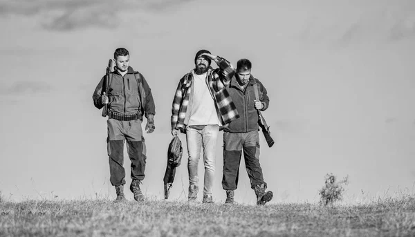 Hunting as hobby and leisure. Hunters with guns walk sunny fall day. Brutal hobby. Guys gathered for hunting. Group men hunters or gamekeepers nature background blue sky. Men carry hunting rifles — Stock Photo, Image