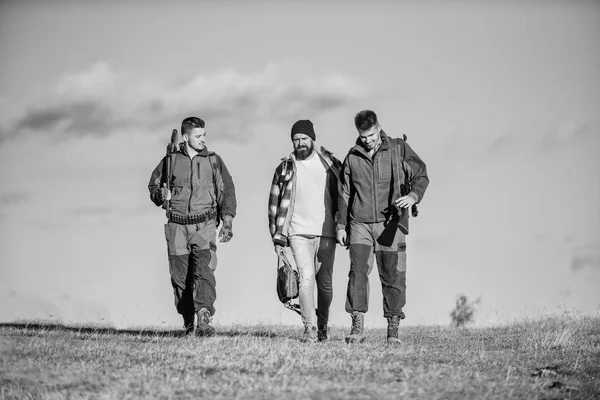 Um passatempo brutal. Grupo homens caçadores ou gamekeepers natureza fundo azul céu. Os homens carregam espingardas de caça. Caça como passatempo e lazer. Caçadores com armas andam dia ensolarado de outono. Rapazes reunidos para caçar — Fotografia de Stock