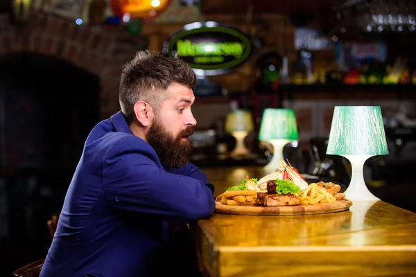 High calorie snack. Relax after hard working day. Businessman formal suit sit at bar counter. Man received meal with fried potato fish sticks meat and lavash. Enjoy meal. He deserve delicious meal