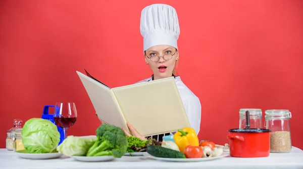 Woman chef cooking healthy food. Girl read book top best culinary recipes. Traditional cuisine. Culinary school concept. Female in hat and apron knows everything about culinary arts. Culinary expert