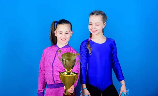 victory of teen girls. Acrobatics and gymnastics. Little girls hold jump rope. Winner in competition. Sport success. Happy children with gold champion cup. hard work brings reward. reward motivation