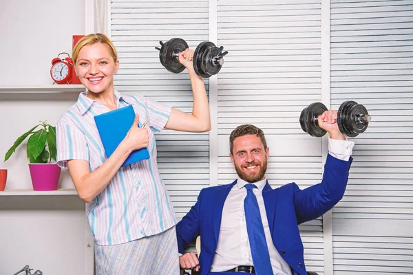 Strong business team. Healthy habits in office. Man and woman raise heavy dumbbells. Strong powerful business strategy. Good job concept. Boss businessman and office manager raise hand with dumbbells