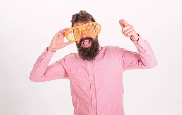 Hipster olhando através de óculos de sol listrados gigantes. Homem com barba e bigode na cara feliz usa óculos engraçados, fundo branco. Conceito de óptica e óculos. Cara com barba de humor alegre — Fotografia de Stock