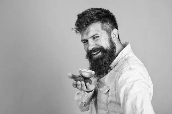 J'ai des friandises pour toi. Hipster barbu tient des fraises et des pommes sur la paume. L'homme propose d'essayer fraises et pommes traite fond bleu. Homme rusé visage avec barbe offre des friandises biologiques — Photo