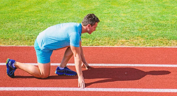 Adam atlet runner standı düşük başlangıç pozisyonu stadyum yolu güneşli bir gün. Zafer için çaba. Runner gitmeye hazır. Yetişkin runner yarış Stadyumu'nda hazırlayın. Nasıl yayınlanmaya başlaması. Spor motivasyon kavramı
