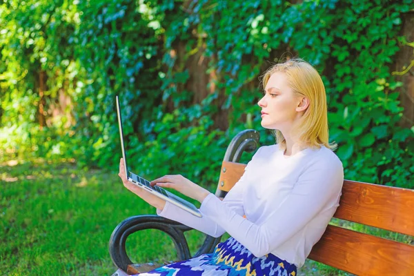 Freelance benefits. Woman with laptop works outdoor, green nature background. Lady freelancer working in park. Advantages and disadvantages of becoming freelancer. Girl sit bench with notebook