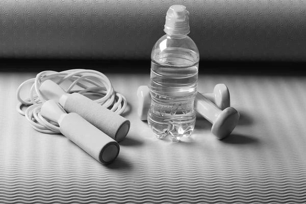 Bottiglia o acqua dolce vicino corda di salto e bilancieri — Foto Stock