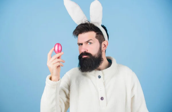 Πασχαλινό. Hipster φορώντας μακριά αυτιά κουνελιού με πασχαλινό αυγό. Το πασχαλινό αυγό είναι σύμβολο της νέας ζωής και της ανάστασης. Γενειοφόρος με στολή πασχαλινού κουνελιού που κρατάει αυγό πασάλ. Παράδοση χρωματιστών αυγών — Φωτογραφία Αρχείου